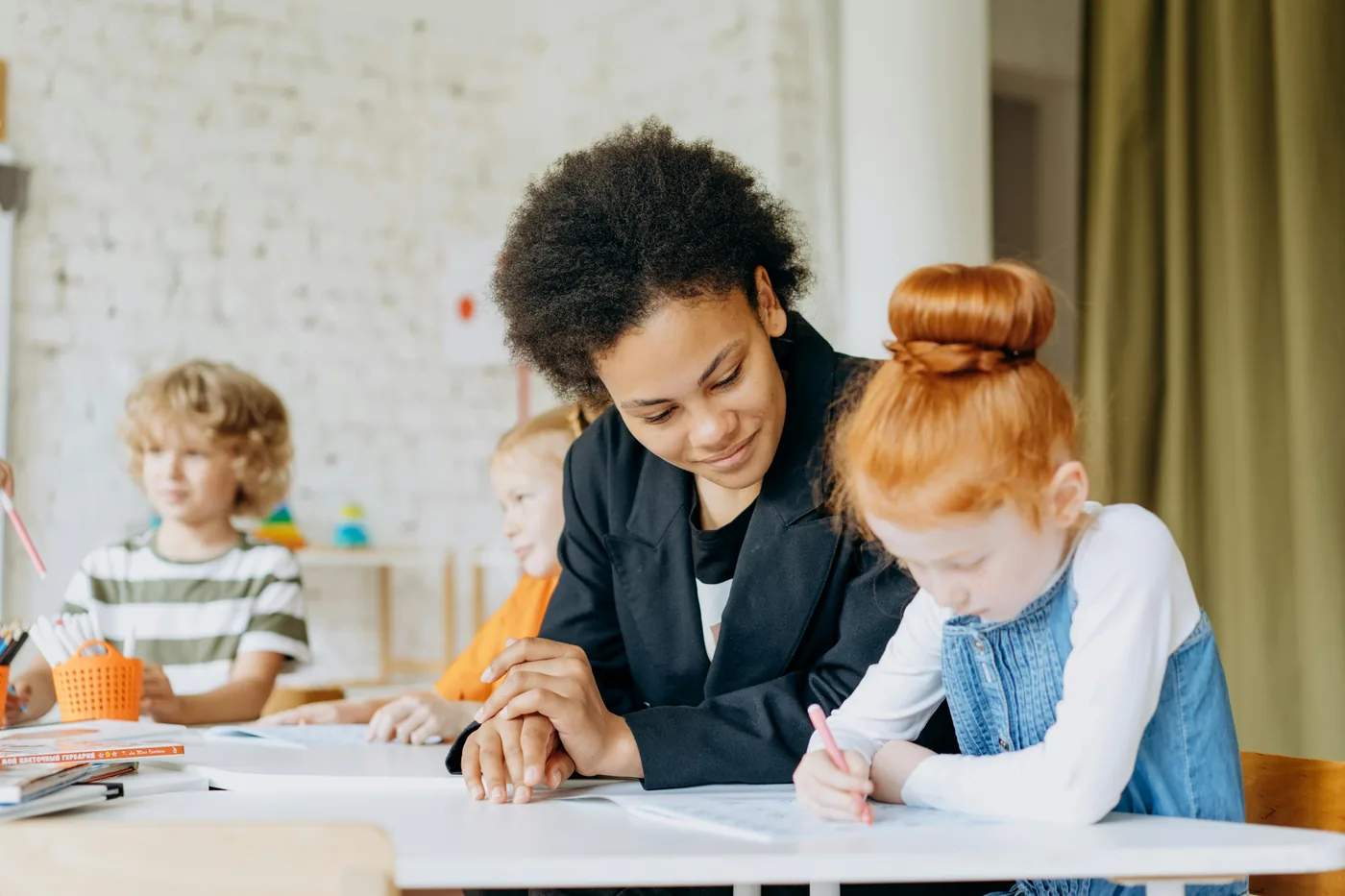A teacher leaning in to help a young student with her work